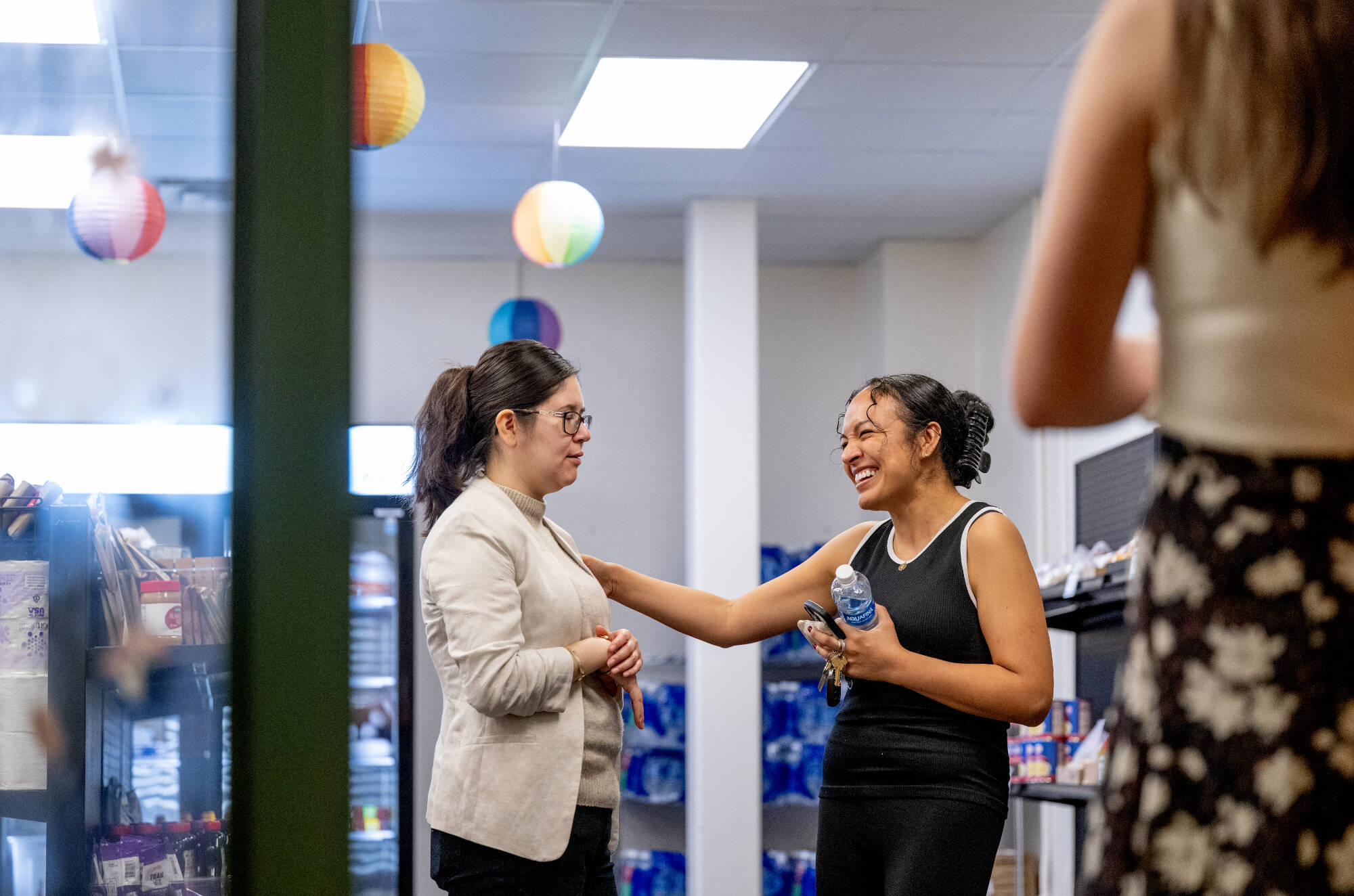 Two individuals share a joyful moment in a brightly lit store, with colorful lanterns hanging overhead.
